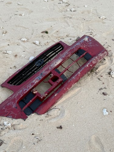 赤い車のバンパーが砂浜に置かれています。