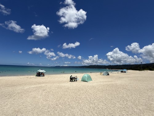 青い海と空の下、白い砂浜にテントが立っているビーチの風景
