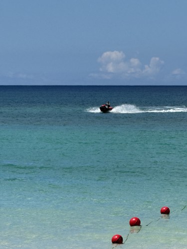 青い海を走るボートと、その手前に浮かぶ赤いブイ