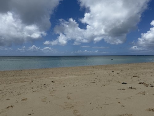 晴れた日のビーチと穏やかな海の風景。青い空に白い雲が広がっている。