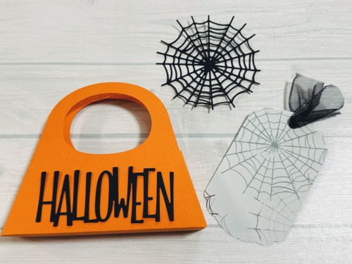 オレンジ色のハロウィンのバッグと黒いクモの巣、透明なクモの巣が置かれている画像