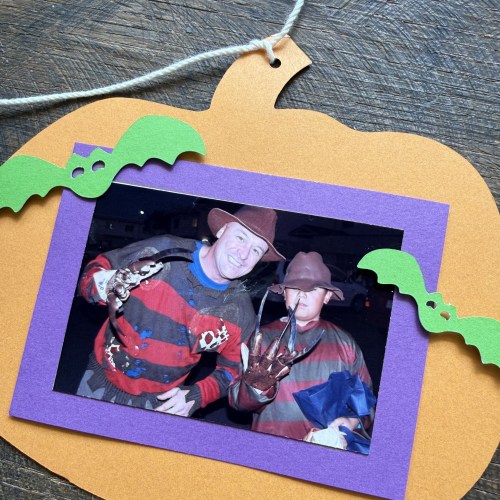 カボチャの形をしたフレームの中に、ハロウィンの衣装を着た2人の男性が写っている写真。
