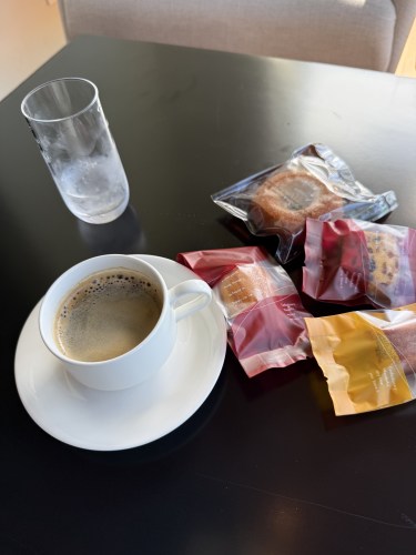 コーヒーカップとお菓子がいくつか置かれたテーブルの上。水の入ったグラスも横にある。