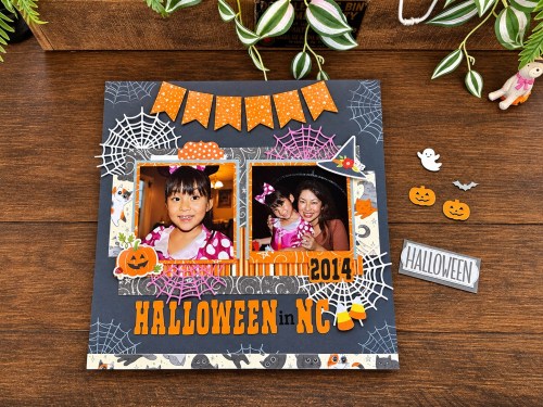 ハロウィンのアルバムページ、2枚の写真があり、オレンジの文字で「HALLOWEEN IN NC 2014」と書かれている。背景にはクモの巣やハロウィンの飾りが散りばめられている。